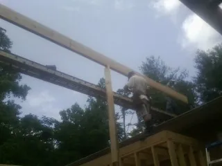 Carpenter setting a ridge beam over a new addition frame — Ice Dam Removal by Roofing Brothers in Mc Kinney