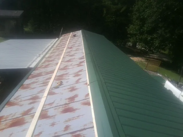 Old rusted panels beside newly installed green metal roofing — Wind Damage Roof Repair by Roofing Brothers in Mc Kinney
