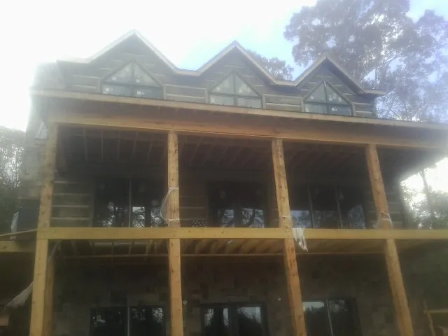 Dormers and porch framing on a large log home under construction — Roof Coating work by our crew in Mc Kinney