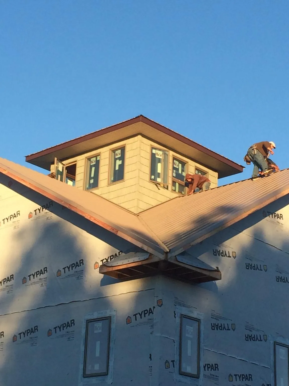 Roofers working around a rooftop cupola on a new metal roof at sunset — Roof Waterproofing in Mc Kinney by Roofing Brothers